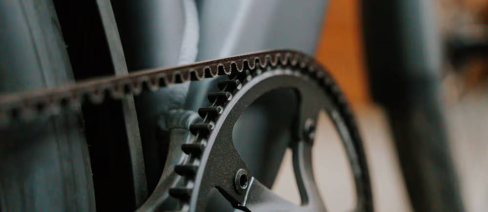 Close-up van een e-bike met riemaandrijving, waarbij de onderhoudsarme belt drive zichtbaar is als alternatief voor een traditionele fietsketting.