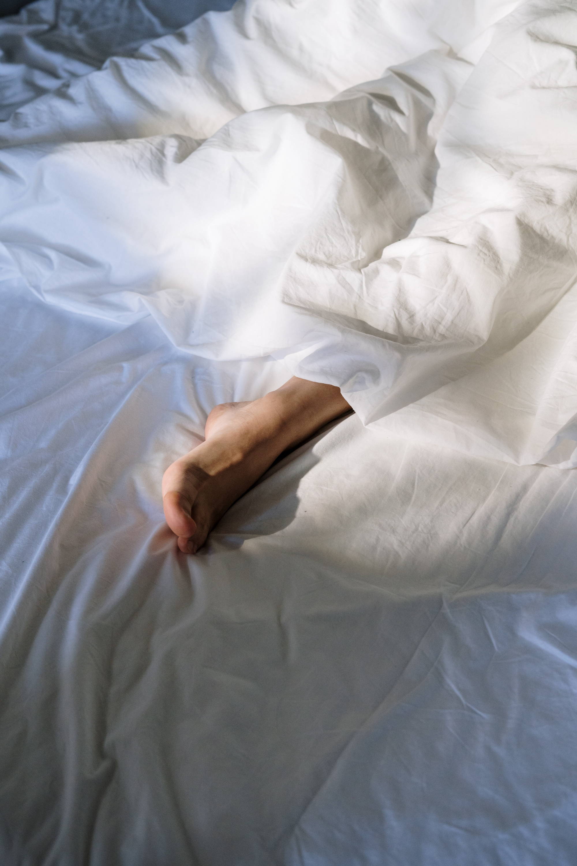 Foot poking out at the end of the blanket - Photo by cottonbro from Pexels