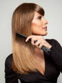 Model using Beautimark wide toothed comb to brush a brunette wig that she is wearing. 
