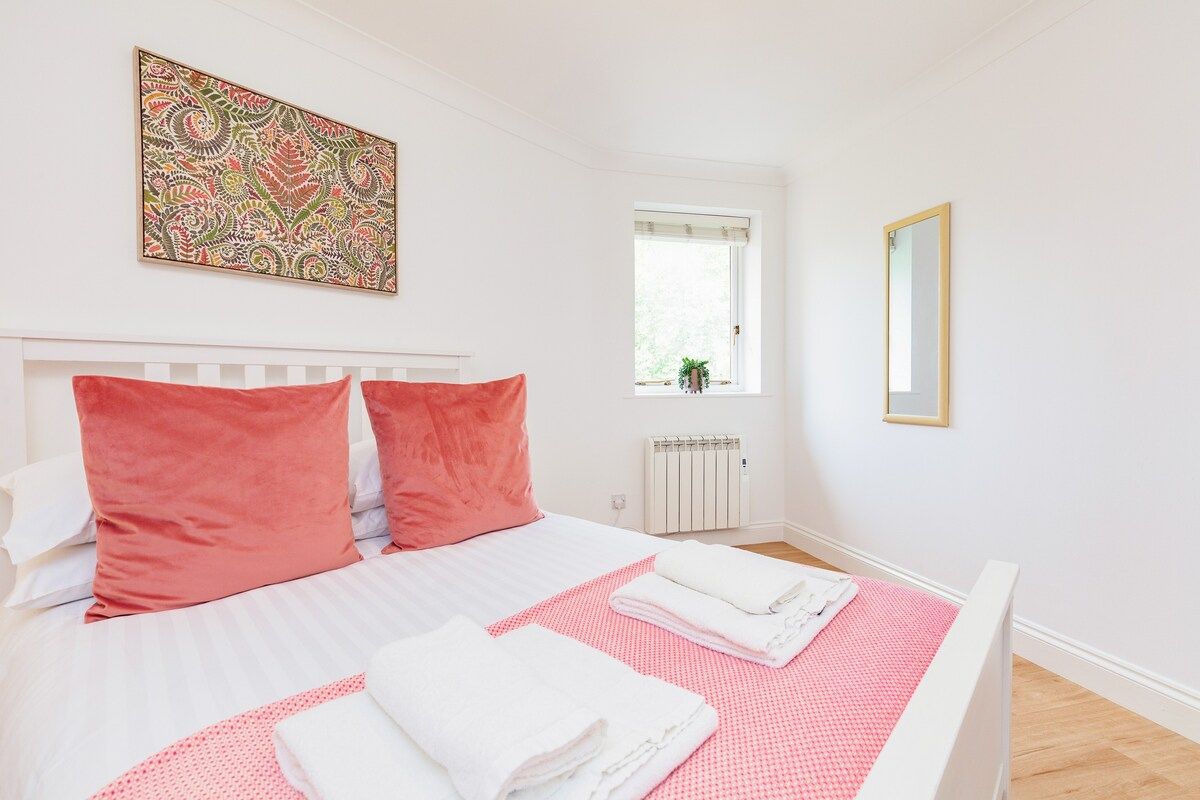 Bedroom with large double bed and pink soft furnishings