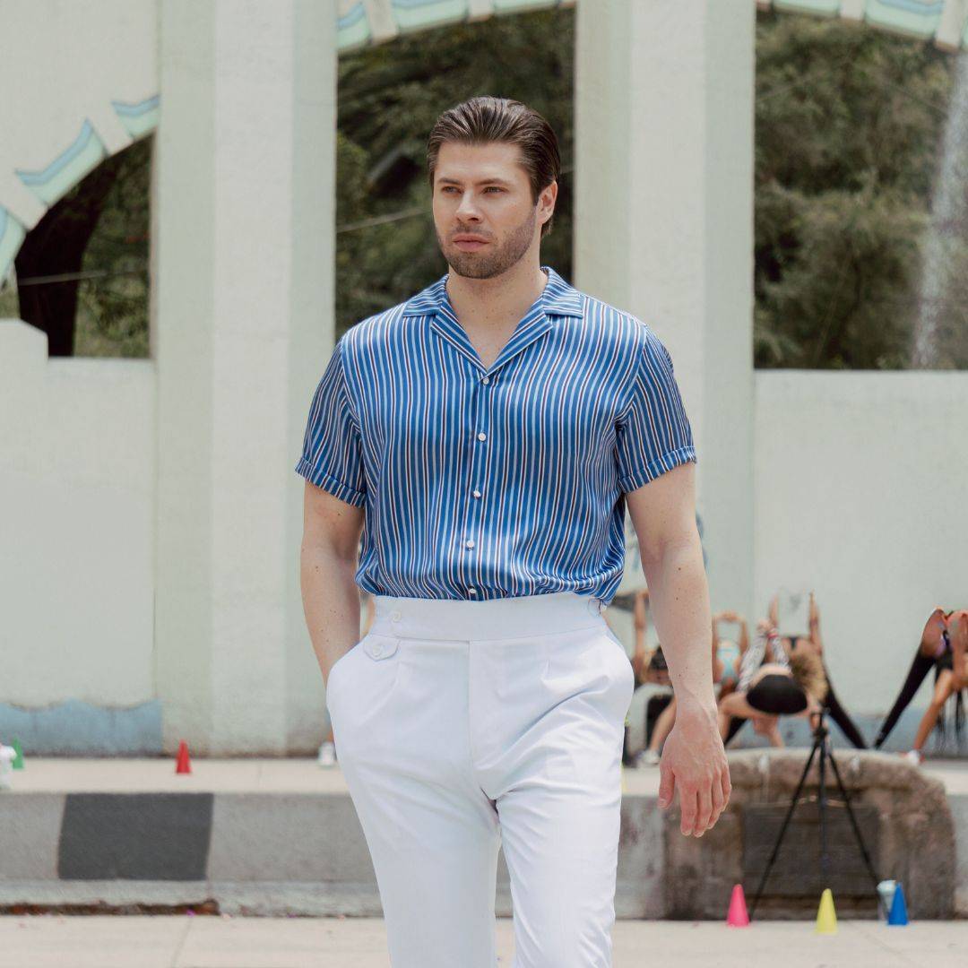 model walking outside and wearing white pants and a short sleeve blue silk shirt from 1000 kingdoms