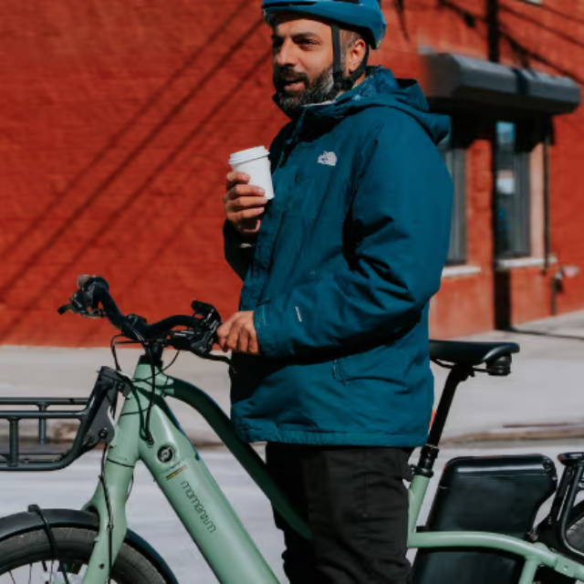 A man on an electric bike drinking a coffee