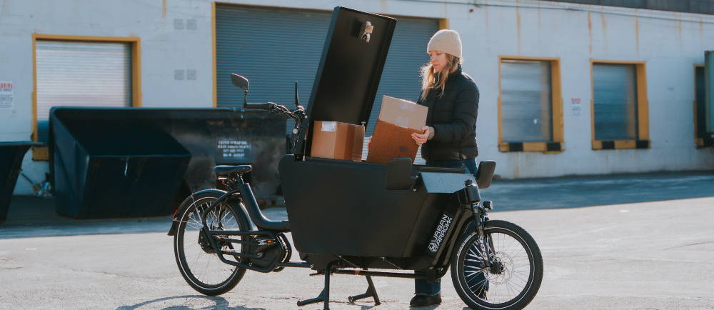 a woman putting boxes into a front loader electric cargo bike