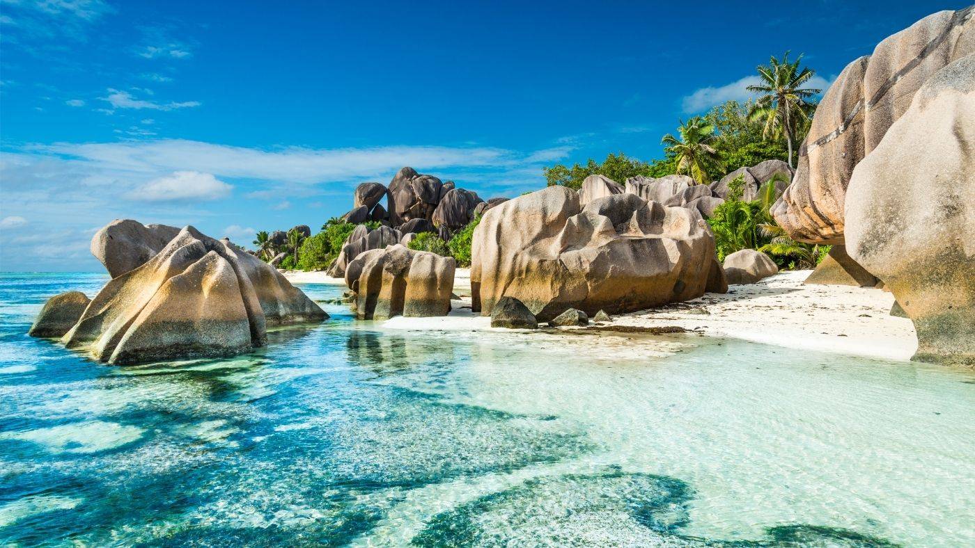 Bambina Seychelles Travel Guide Granite Rocks in Ocean Surrounded by Palm Trees