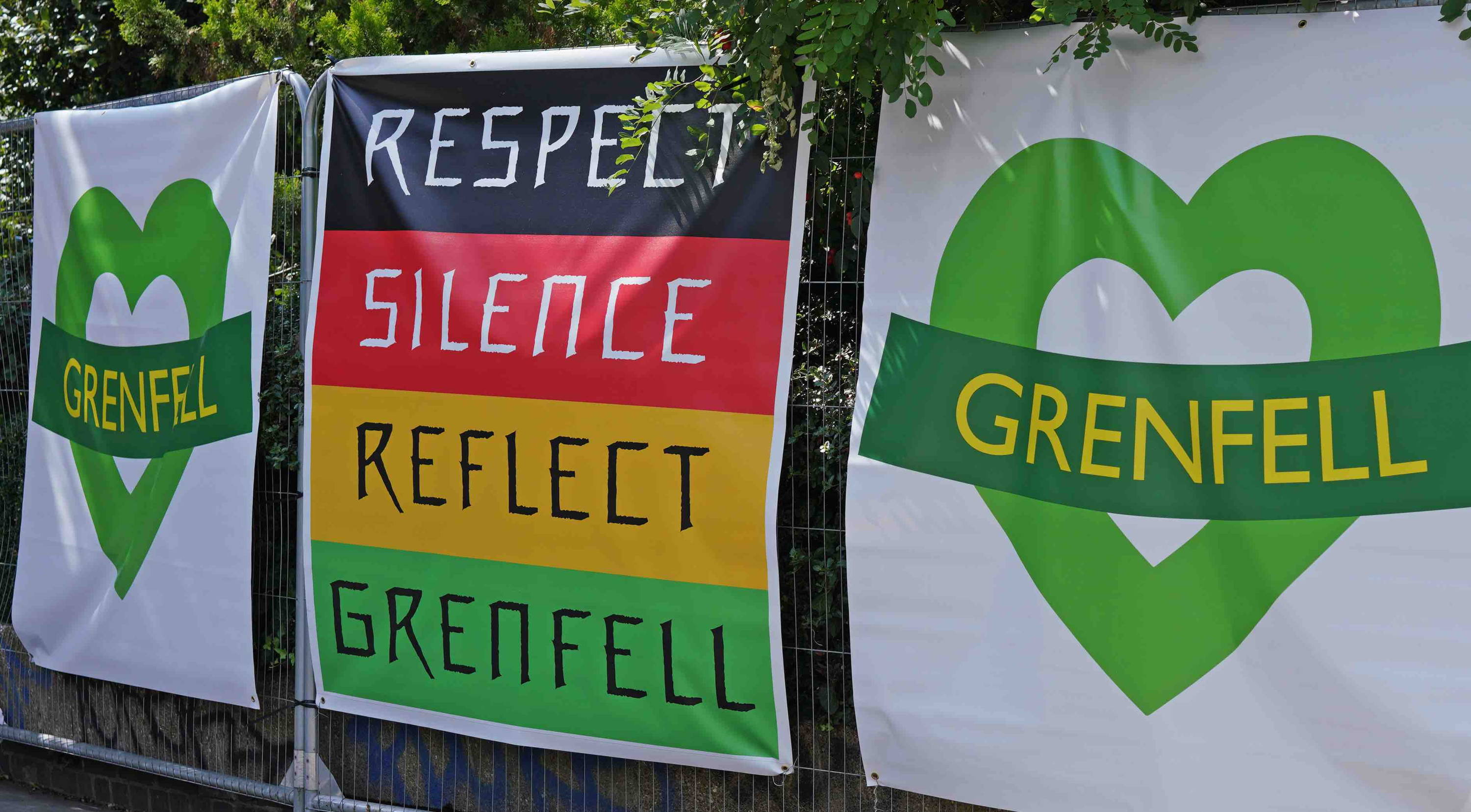 Grenfell green hearts and sign reading: respect, silence, reflect, Grenfell