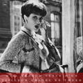 Mannequin Marie-Hélène Arnaud vêtue d'un tailleur Chanel en tweed et fumant une cigarette
