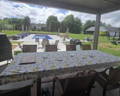 rectangular oil cloth on tan outdoor table besides a pool