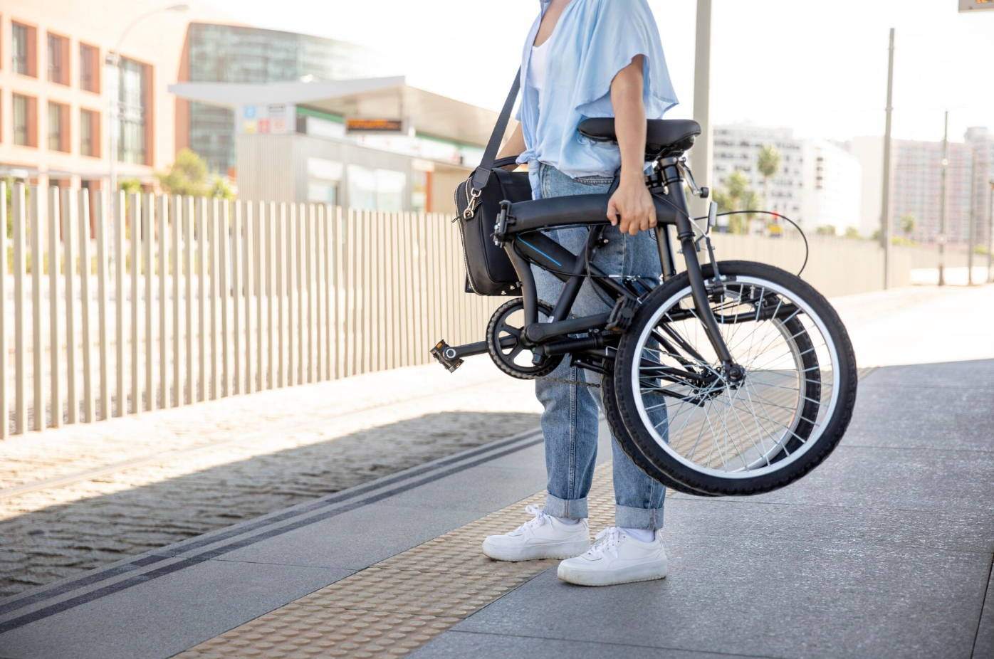 Une femme prend son vélo électrique pliant acheté chez ShiftBikes pour prendre le métro