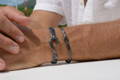 A man's hand wearing ocean fishhook bracelets.