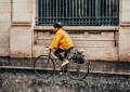 Cycliste sous la pluie, en ville, portant un poncho jaune et un casque noir