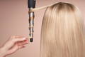Blonde woman from back with hair curler curling keratin treated hair