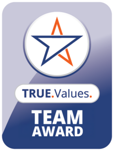 Award badge featuring a stylized star in blue and orange, with the text TRUE.Values. TEAM AWARD below on a gradient blue and purple background.