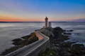 Un chemin pavé qui mène à un phare en bord de mer