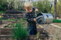 Little boy watering plants in the garden. 