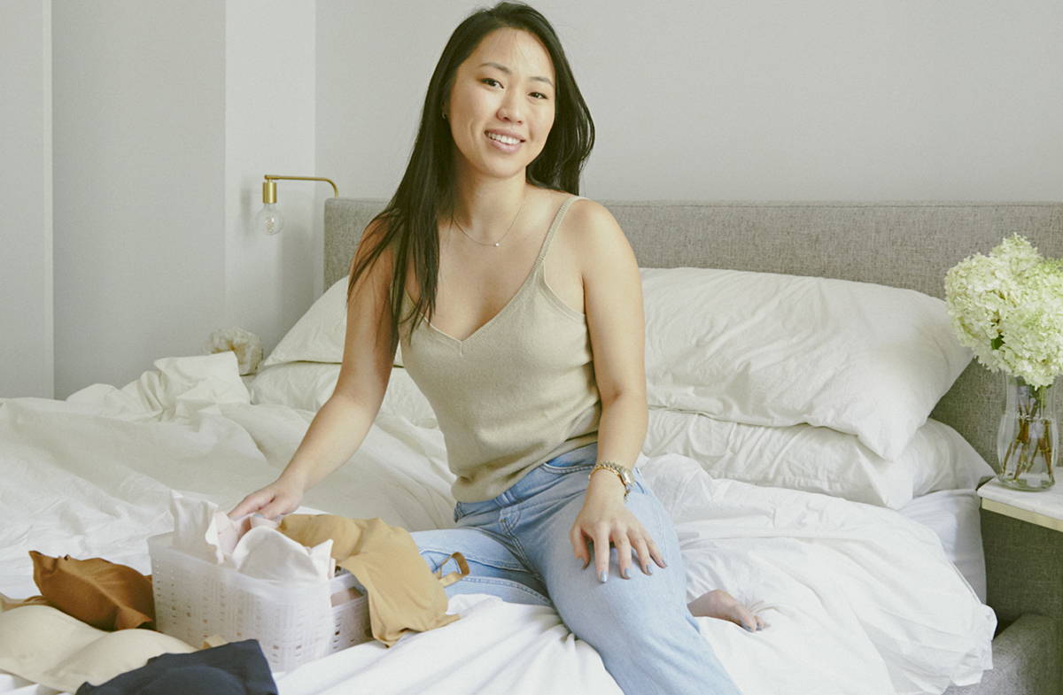 Founder of okko, Phoebe Kunitomi, sits on her bed with her minimalist bra designs.
