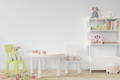 Children's room with white furniture and wooden toys inspired by Montessori method. 