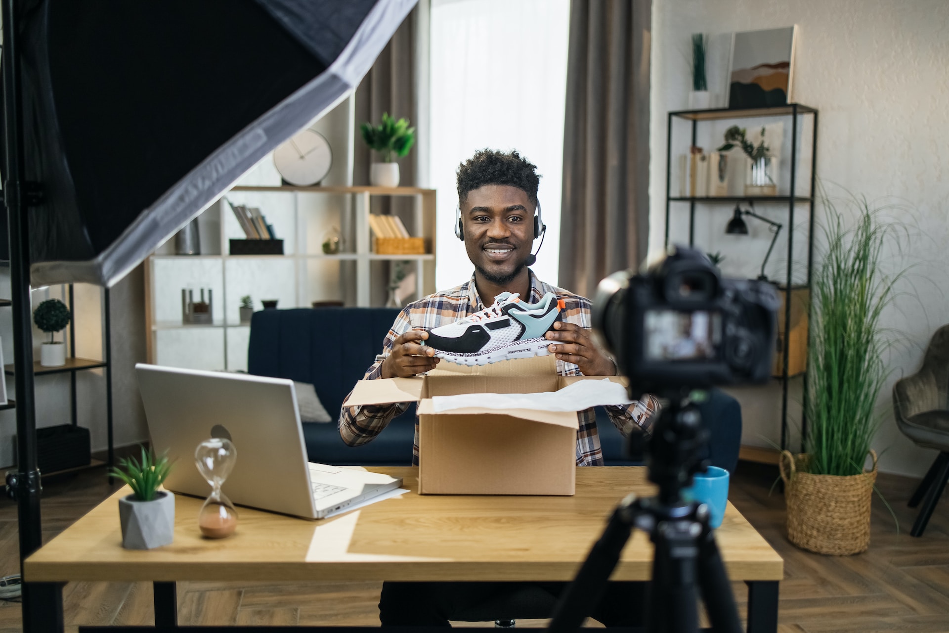 A content creator sits in front of a camera holding up a new pair of unboxed trainers