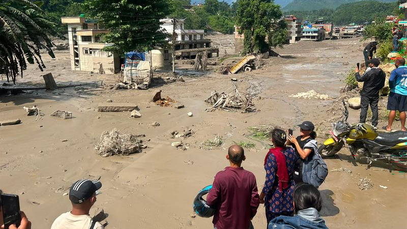 Residents look at houses partially submerged in muddy water after flash floods in Nepal.