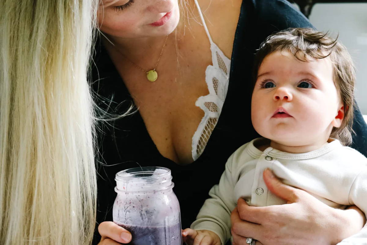 mom drinking pre-workout holding her baby