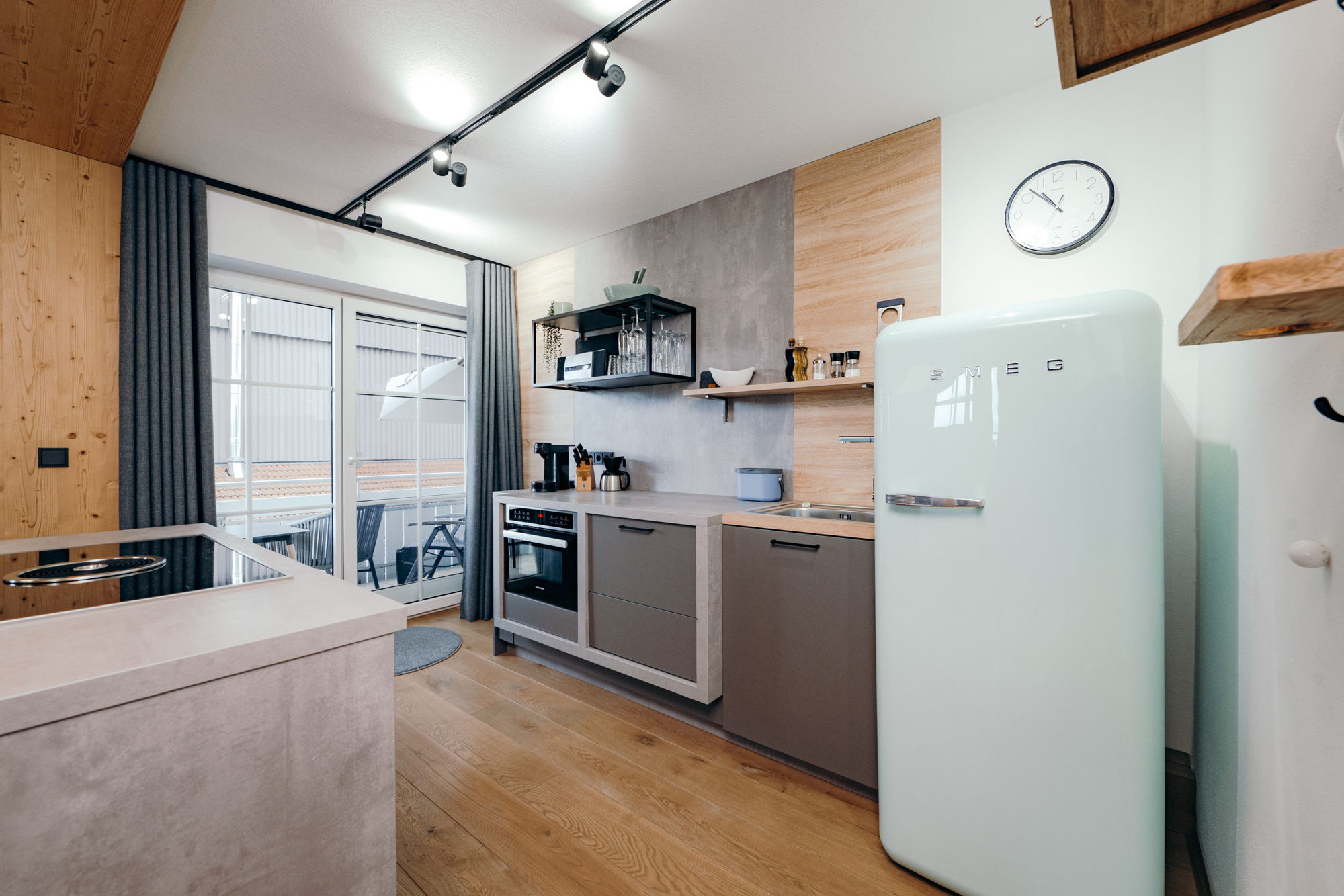 Eine moderne Küche mit steinernen Arbeitsflächen und einem hellen Kühlschrank.