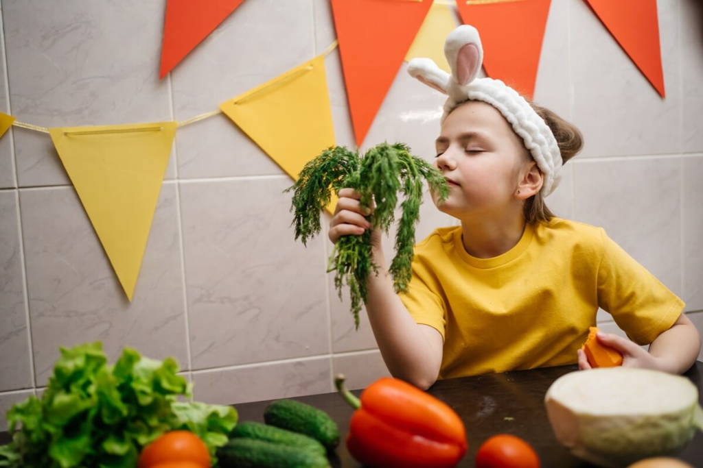 Petite fille portant des oreilles de lapin et sentant des légumes.
