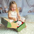 Toddler opening a Christmas box and taking out the Montessori Santa's Book. 