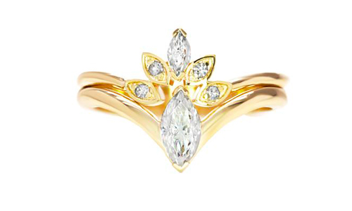Bagues de fiançailles et de mariage en or jaune avec diamants placées l'une par dessus l'autre sur fond blanc