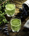 two glasses of green smoothie with blueberries added