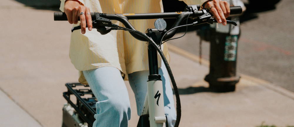 a woman riding a specialized electric cargo bike on a sidewalk