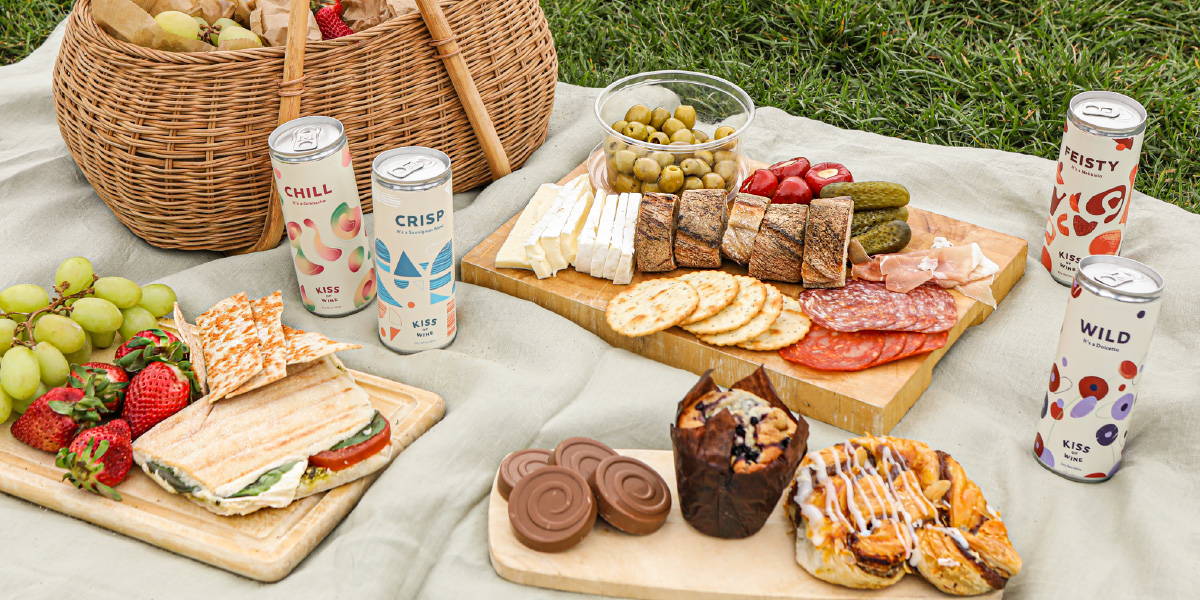 Picnic spread of toppings to go with baguettes and crackers paired with our light Kiss of Wine range on a summer's day.