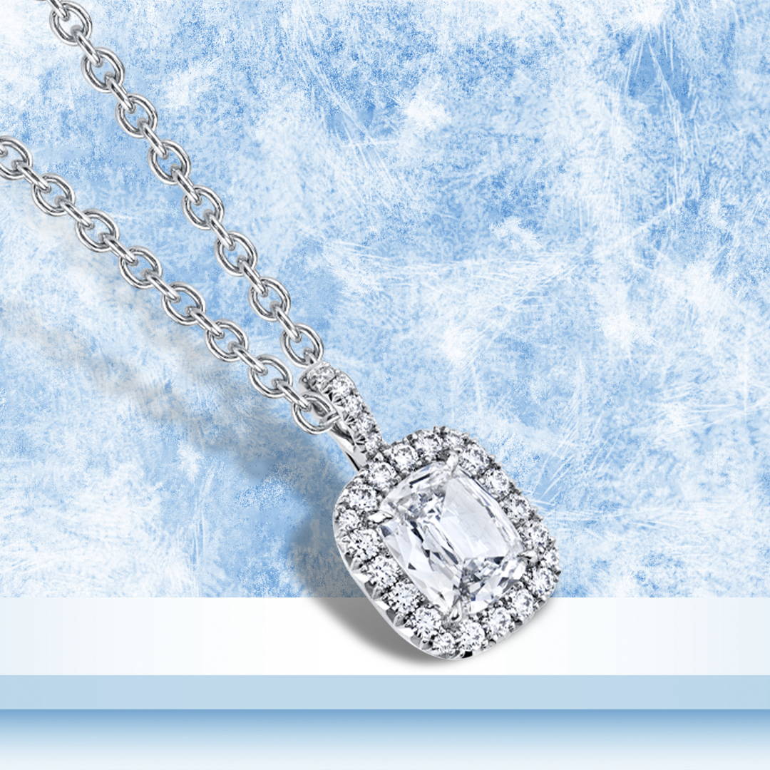Cushion cut diamond pendant with diamond halo in platinum on a blue background