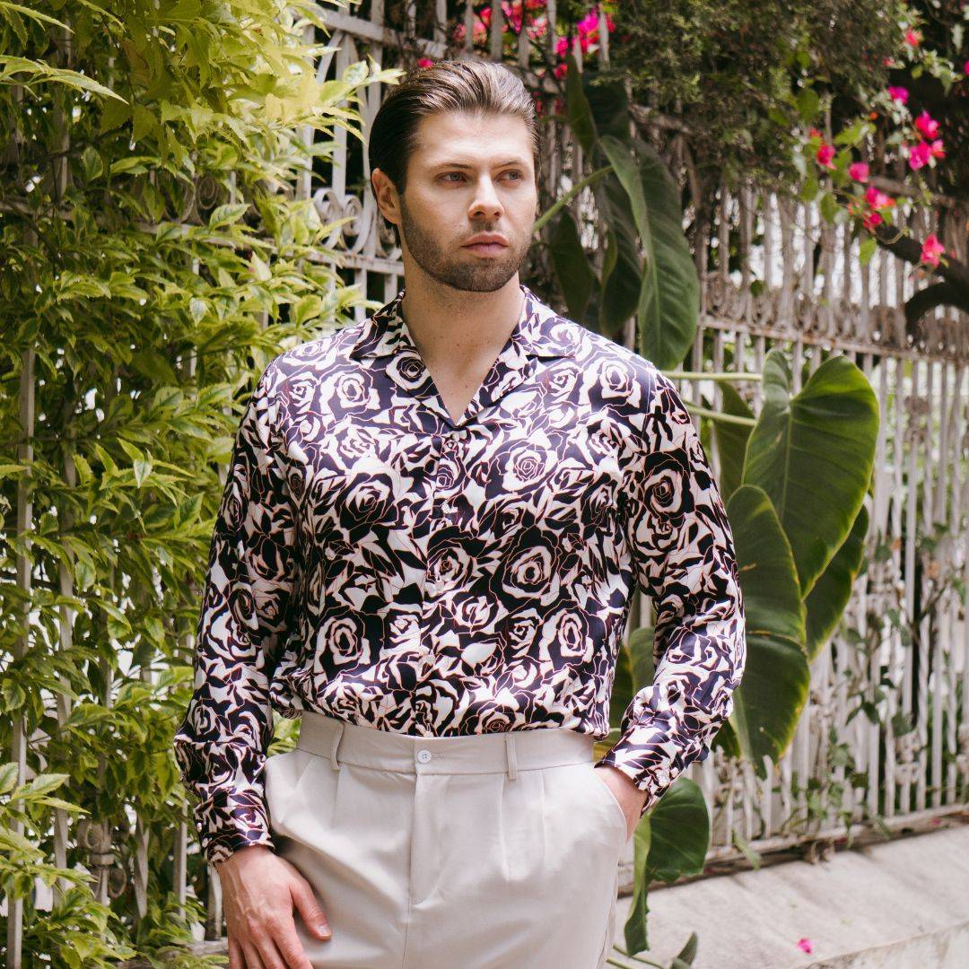 model standing outside wearing white high rise pants and a long sleeve navy floral silk shirt from 1000 kingdoms