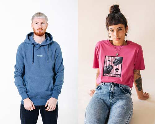 Man wearing washed out blue organic cotton hoodie with small Wawwa embroidered branding in the middle chest and woman wearing acid wash denim with an organic cotton bright pink t-shirt with a space inspired pink, white and black graphic illustration both from sustainable fashion brand Wawwa