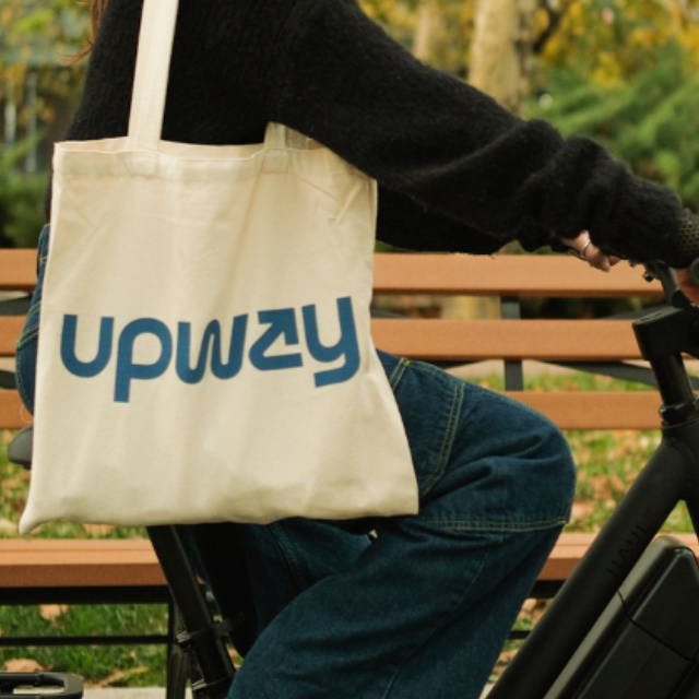 a woman riding an electric bike and carrying an Upway bag