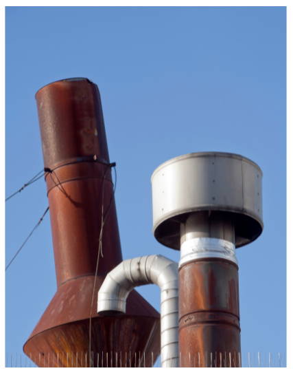 Rusted metal chimney flue and vent pipes showing corrosion from long-term weather exposure