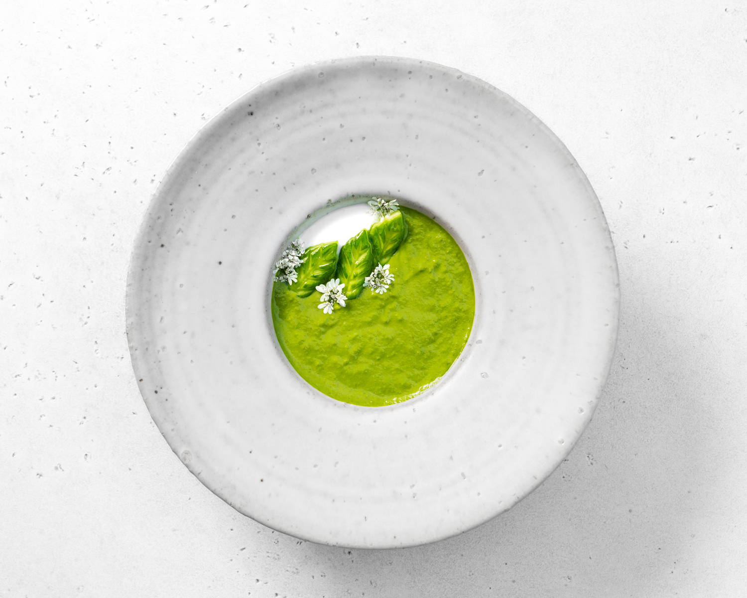 A vivid green, cold soup decked with white flowers, asparagus heads and a dollop of yogurt.