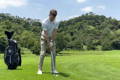 Golfer showing neutral grip position and square stance before swing on green course fairway