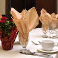 napkins of orange color inside cups over a table with curtailery