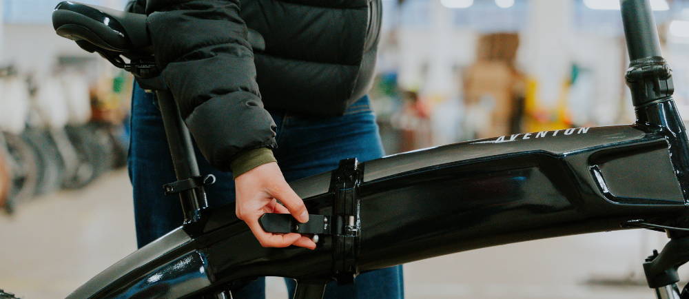 Rider releasing the center frame latch of Aventon Sinch folding e-Bike