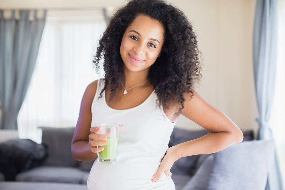 young woman looking at camera with green smoothie in her glass