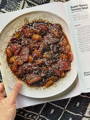 A picture in a cookbook of a Super Savory Tomato salad, shown laying on a decorated ceramic plate topped with sesame seeds