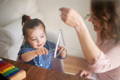 Mother holding a triangle and showing her daughter how to play it. 