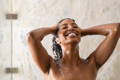 woman rinsing hair under shower 