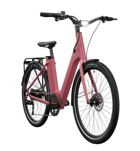Roze Lidl Crivit e-bike met lage instap, bagagedrager, geïntegreerde verlichting en schijfremmen, schuin van voren afgebeeld op een lichtgrijze achtergrond.