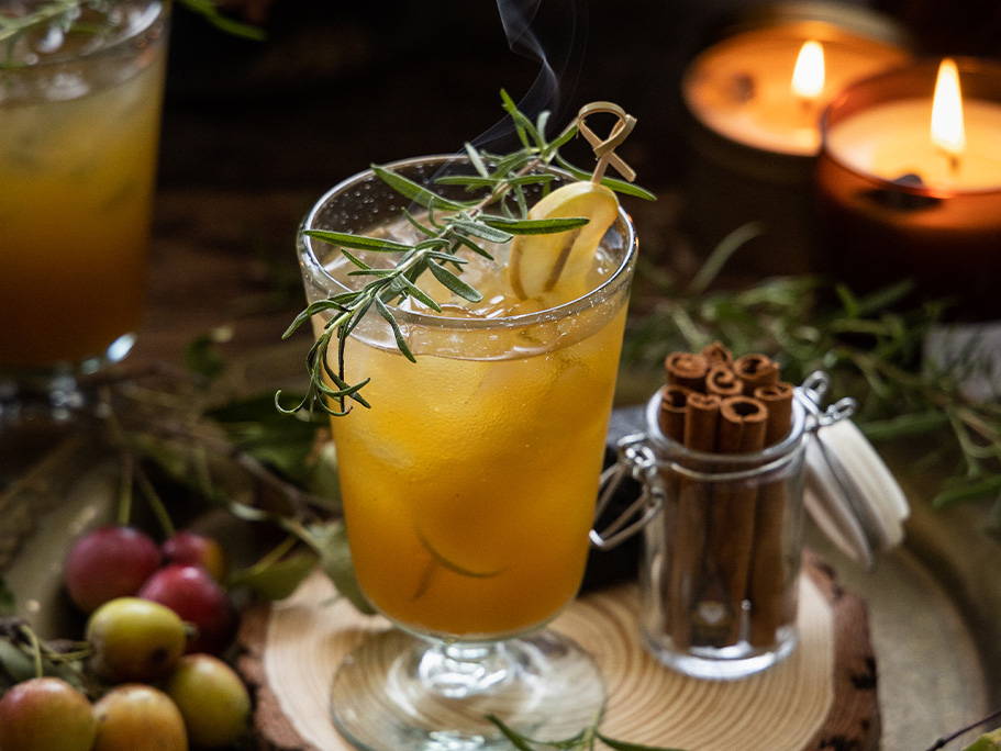 Rosemary garnish on top of an apple cider based cocktail