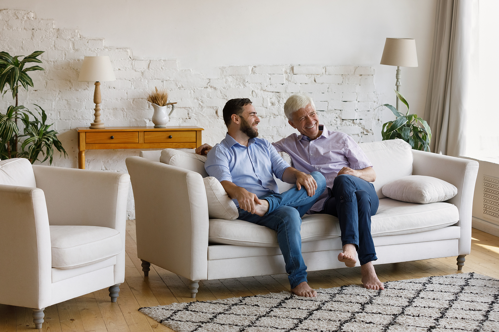 Cheerful man his senior father talking sit on sofa.