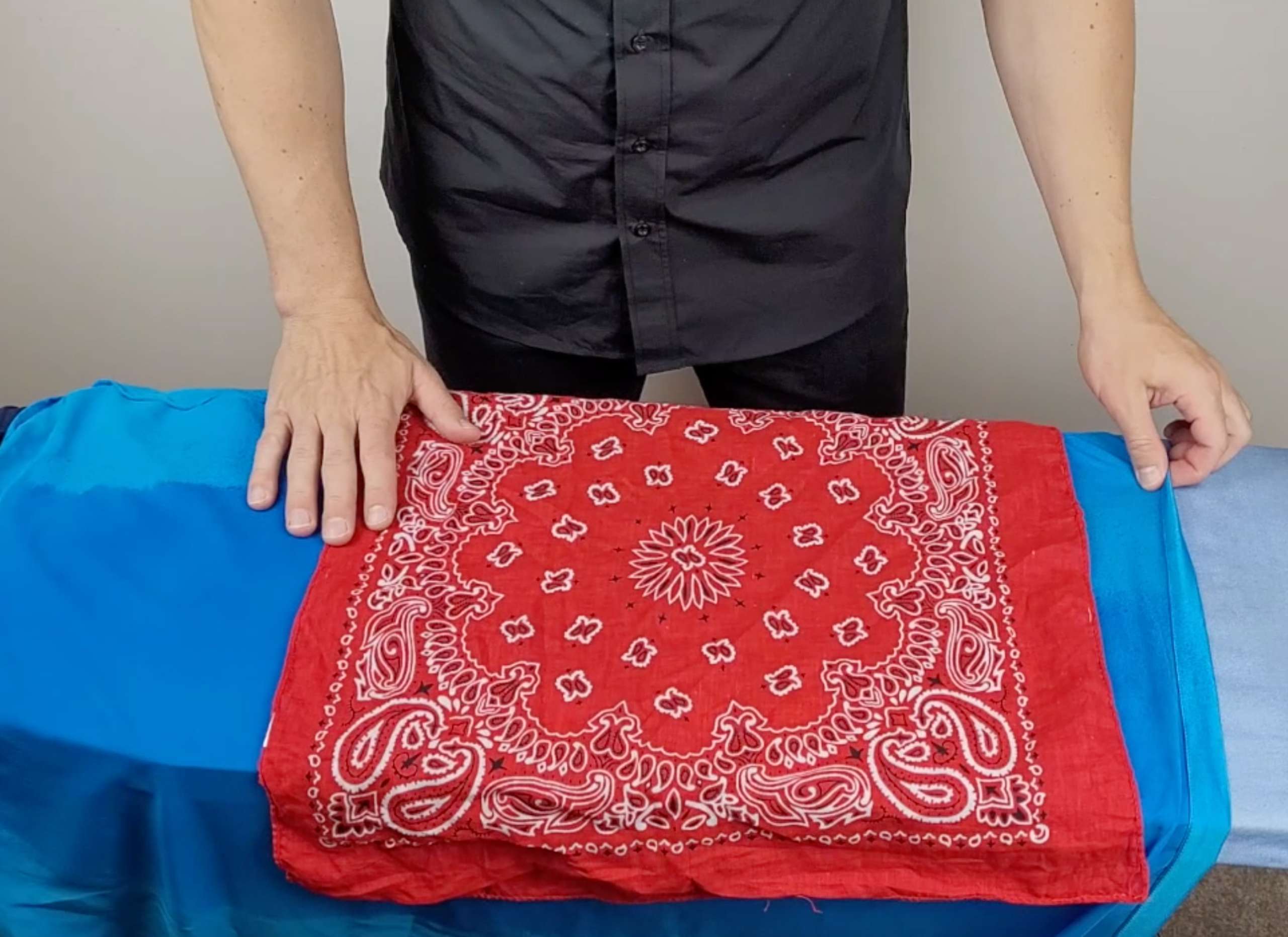 an image of a man placing a cotton bandana on top of a silk shirt