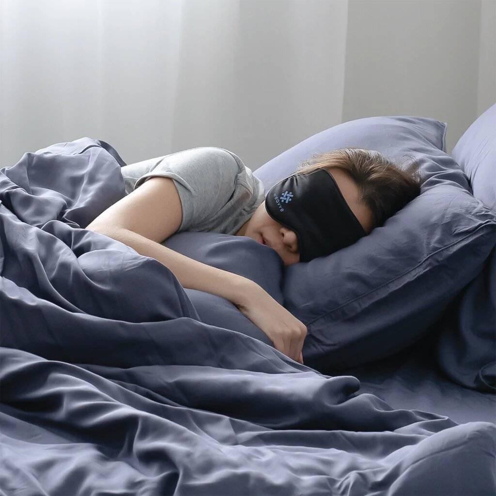 Woman with Weavve's eye mask sleeping on TENCEL bed sheets