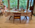 oval oil cloth over a table inside an apartment with a window looking a tree