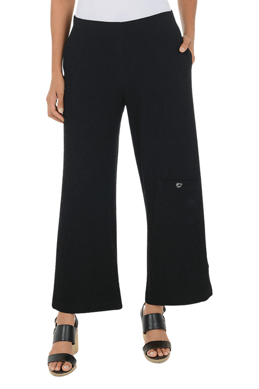 A woman wearing a black wide leg pant against a beige background